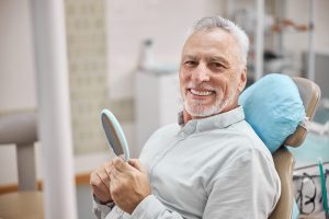 senior man sitting in dental chair smiling