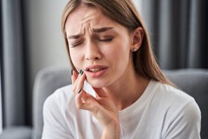 woman holding cheek in pain