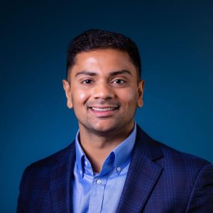 Dr. Niral Patel, DMD, FICOI, smiling in a professional setting, representing Fountain City Smiles, specializing in custom sports mouthguards and dental care for athletes.